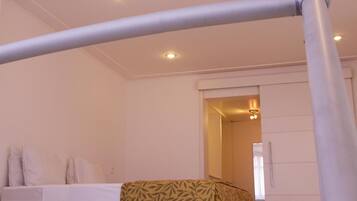 Quarto de hotel com cama, manta estampada e teto com iluminação embutida.