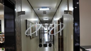 A hotel corridor with a tiled floor, doors on both sides, and a sign reading "EMPURRER" on the right wall.