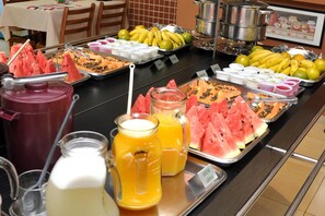 A buffet with various fruits, juices, and a pot of soup. - Carolina Plaza Hotel (Uberaba)