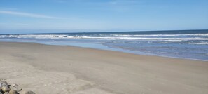 Una playa con una amplia orilla de arena y olas suaves.