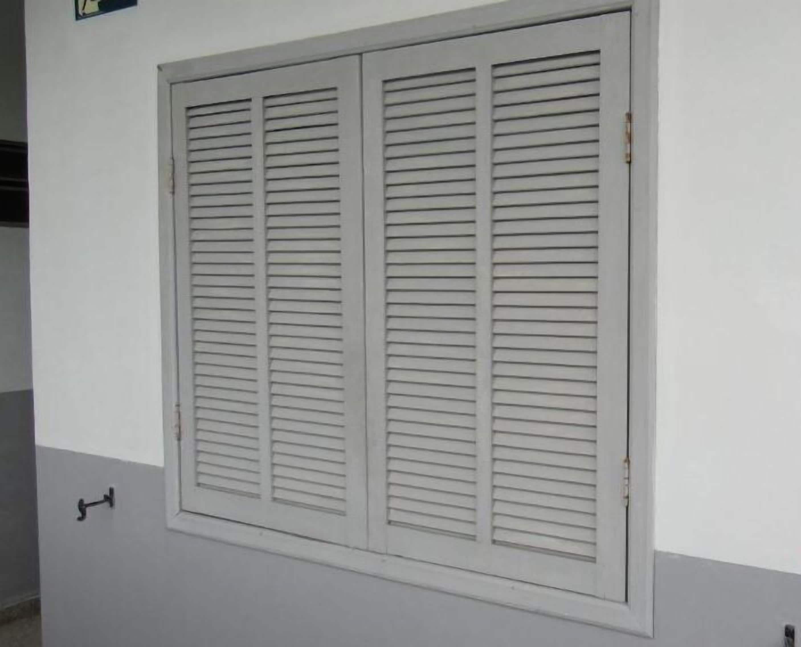 A large window with horizontal blinds, a visible door handle, and a small sign above the window.