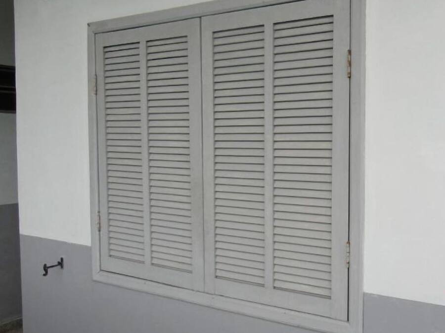 A large window with horizontal blinds, a visible door handle, and a small sign above the window.