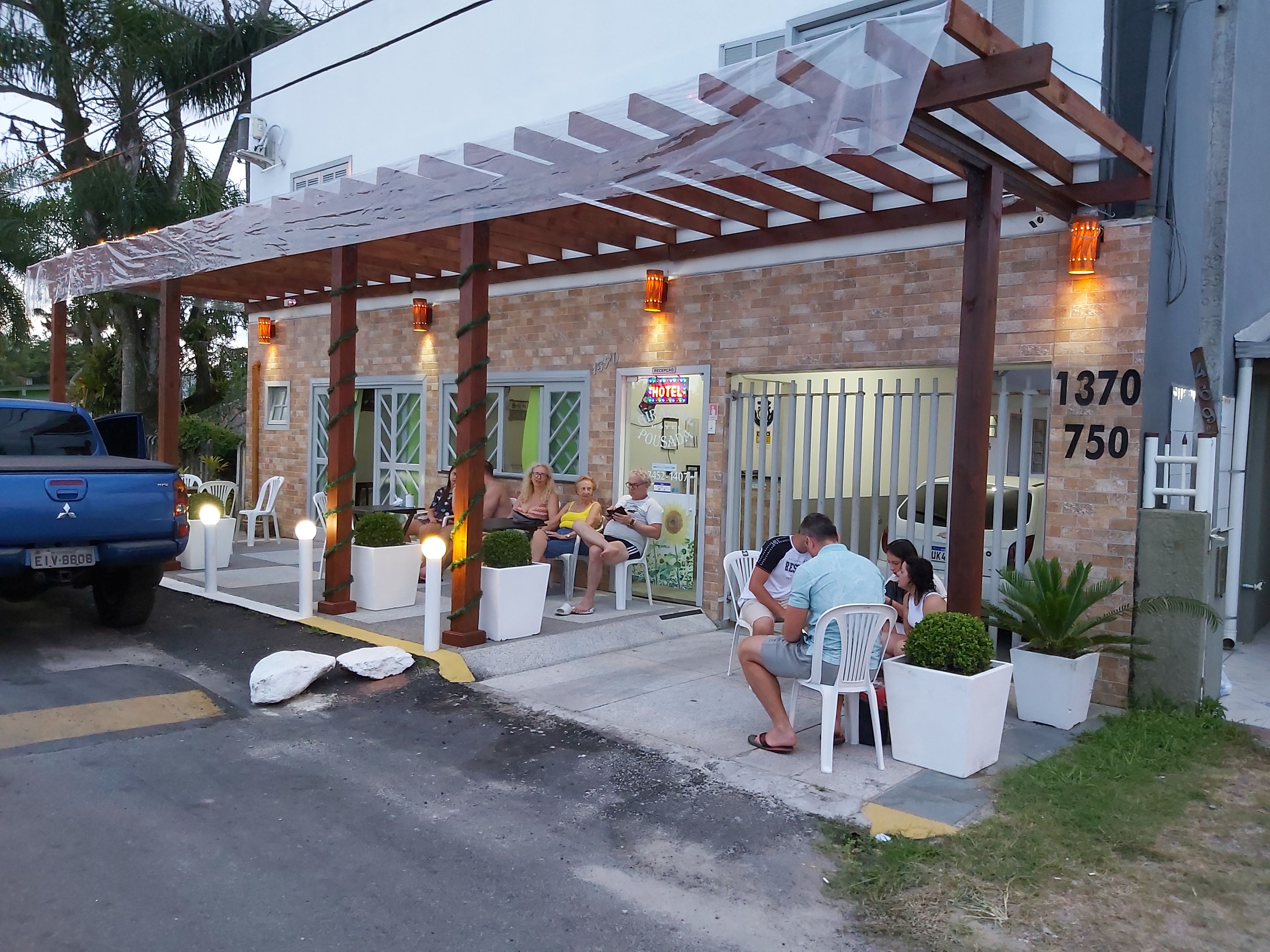 A hotel with a covered patio area, outdoor seating, and a brick facade.