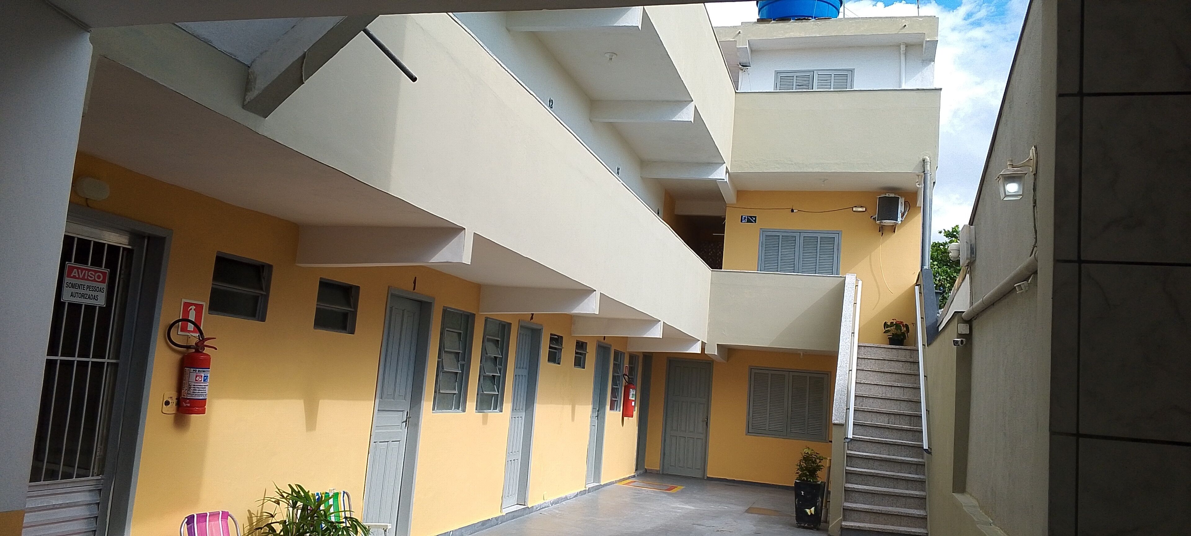 A multi-level residential building with balconies, a fire extinguisher, and a stairway.