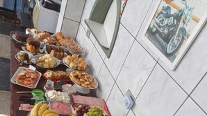 A buffet table with various food items including fruits, cheeses, and pastries. - Pousada Girassol (Matinhos)