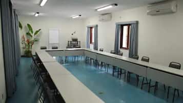 Ein Konferenzraum mit langem Tisch, Stühlen und einer Projektionsleinwand.