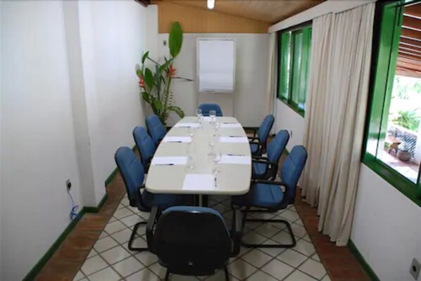 A conference room with a long table, blue chairs, a whiteboard, and a plant. - Hotel 7 Colinas (Olinda)