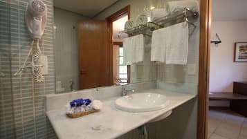 A bathroom with a white sink, a hairdryer mounted on the wall, and a towel rack with multiple towels.