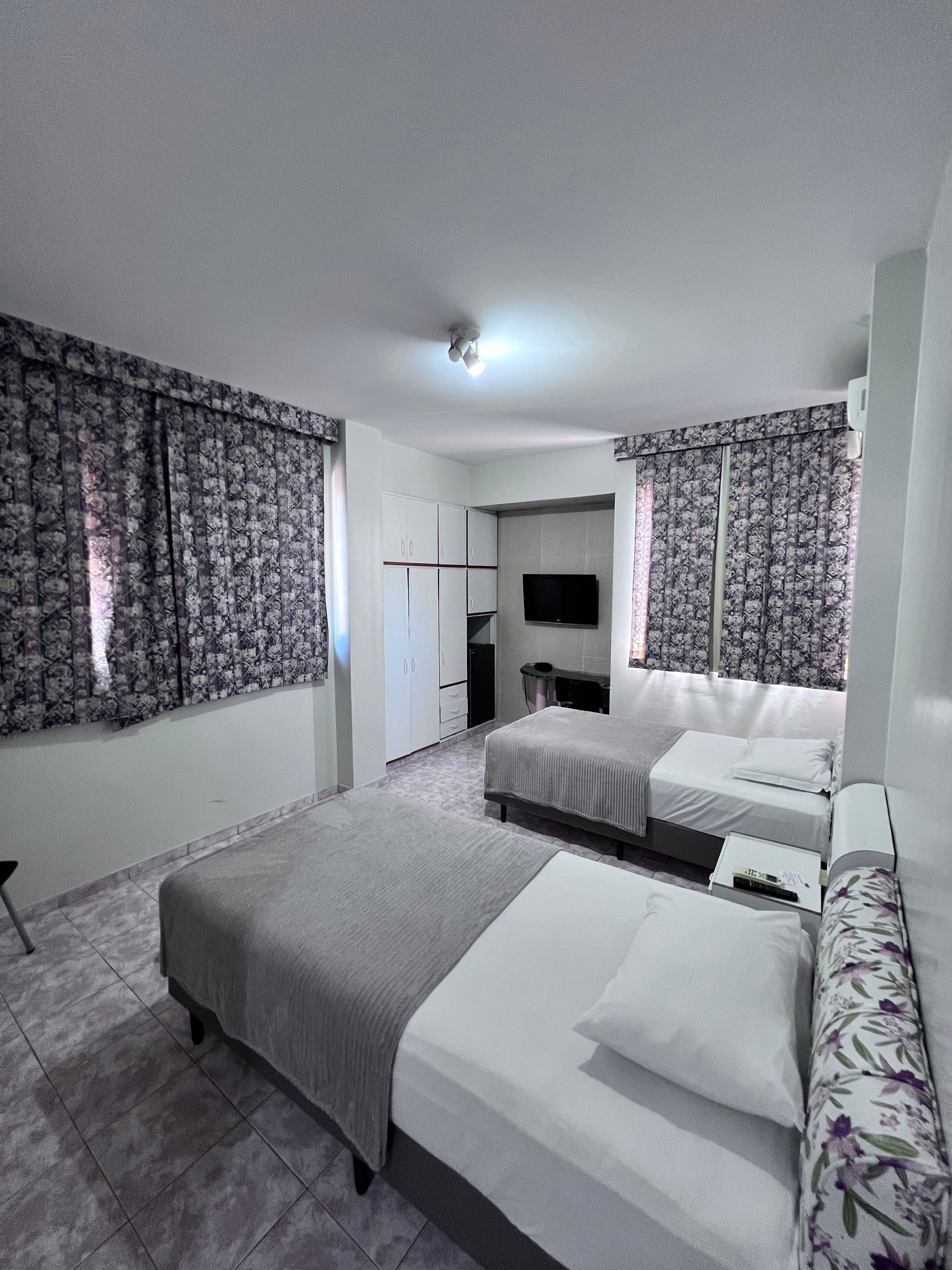 A bedroom with two beds, a TV, and a wardrobe.