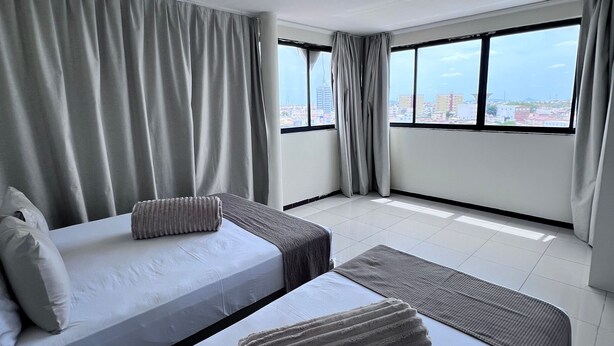 Une chambre d’hôtel avec deux lits, une vue sur la ville et une grande fenêtre.