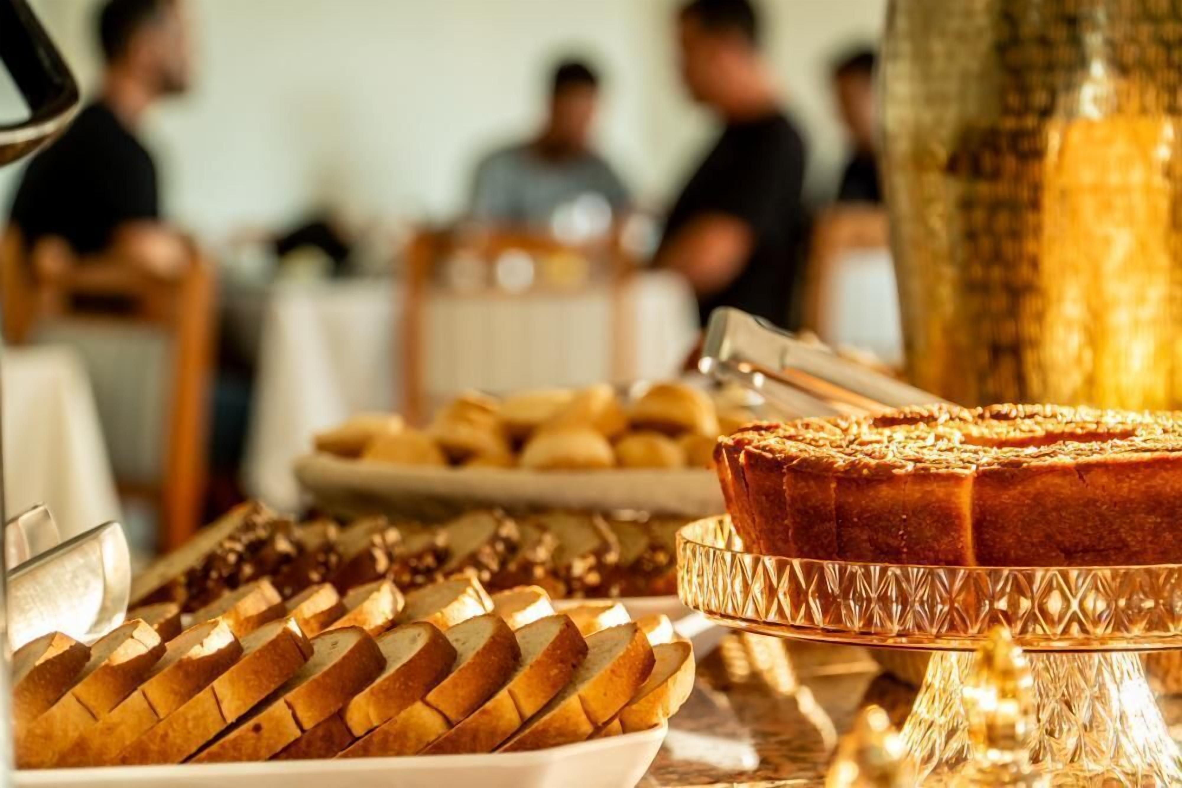 A buffet table with sliced bread, a cake, and various pastries.