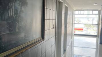 Un pasillo con un cuadro enmarcado en la pared, un sofá azul y vistas a un edificio.