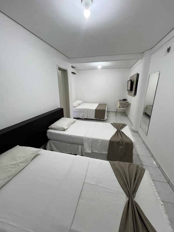 Una habitación de hotel con dos camas, un escritorio, una silla, un espejo y un televisor.