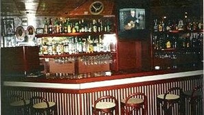 A bar area with a counter, shelves of bottles, and four chairs. - Arcada Hotel E Bistrô (RECIFE)