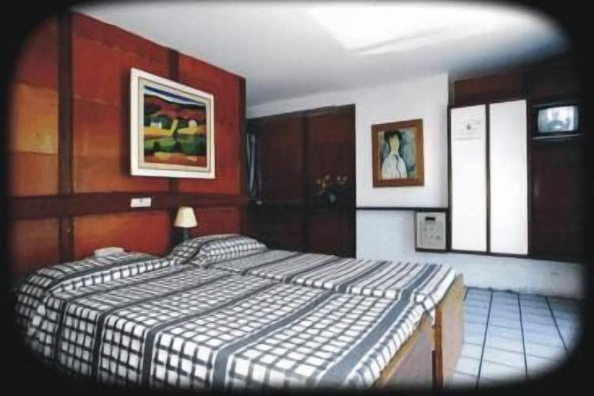 A room with a bed, a painting on the wall, and a door.