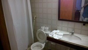 A bathroom with a toilet, two rolls of toilet paper, a sink, and a mirror. - Arcada Hotel E Bistrô (RECIFE)