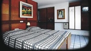 A room with two beds, a painting on the wall, a lamp, and a television. - Arcada Hotel E Bistrô (RECIFE)