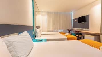 Una habitación de hotel con dos camas, un escritorio, una silla, un televisor y un ventanal con cortinas.