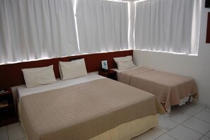 A hotel room with two beds, a nightstand, and a window with white curtains. - Rede Andrade Navegantes (Recife)