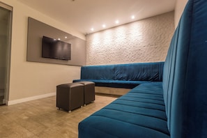 Una sala de estar moderna con un sofá seccional, un televisor de pantalla plana montado en la pared y un papel tapiz estampado.