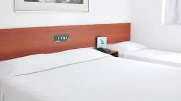 Habitación de hotel con dos camas, cabecera de madera, una obra de arte enmarcada en la pared y una mesita de noche con lámpara.