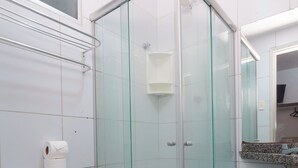 Ein Badezimmer mit Duschkabine aus Glas, Toilette und Waschbecken mit Spiegel darüber.