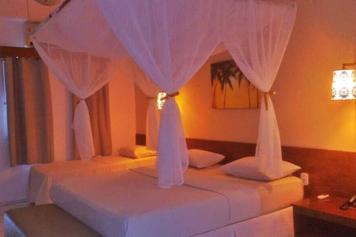 A hotel room with a bed, a nightstand, a lamp, and a painting on the wall.