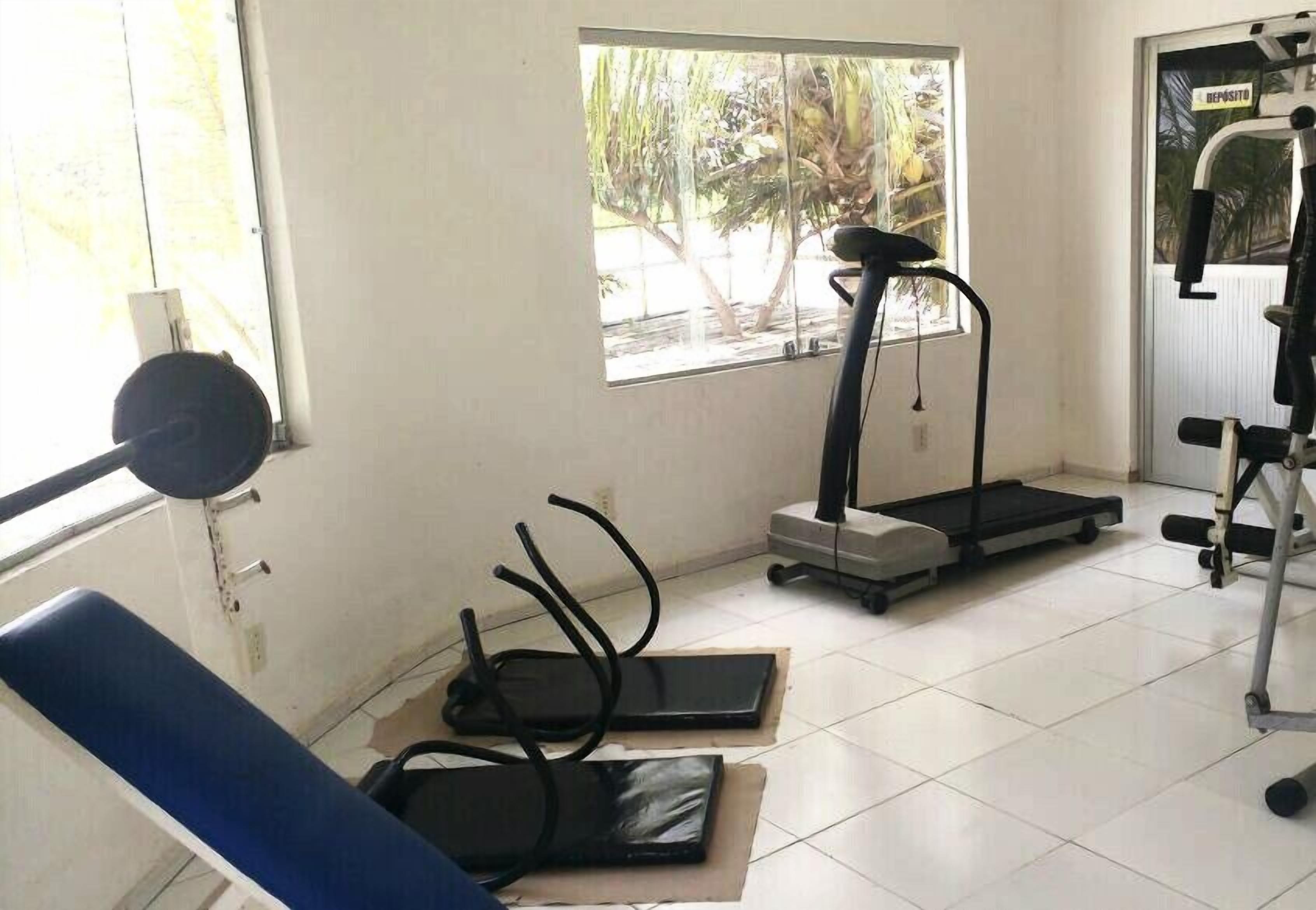 A gym with exercise equipment including a treadmill, stationary bike, and weights.