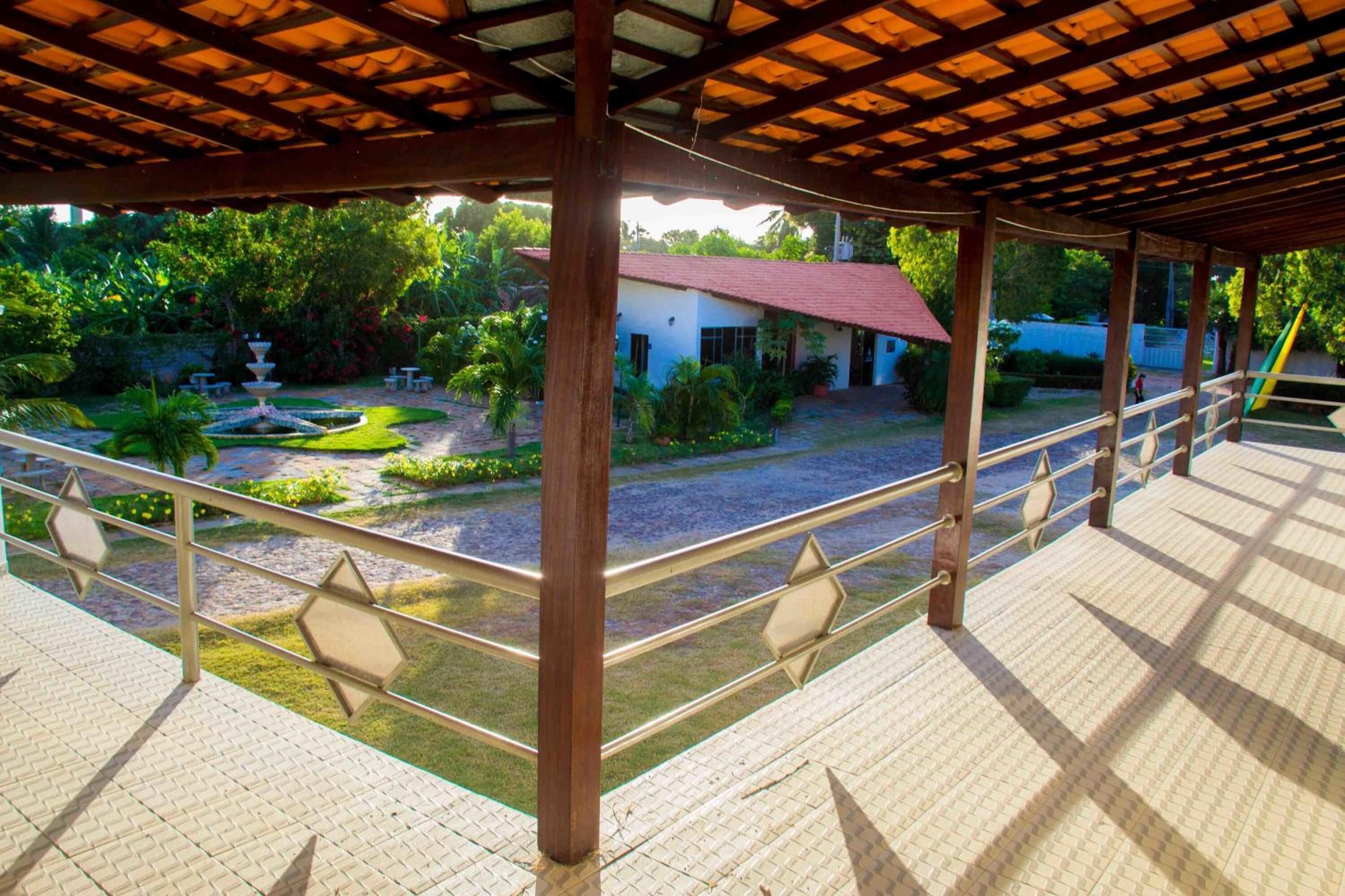 Área externa coberta com vista para um jardim e um edifício.
