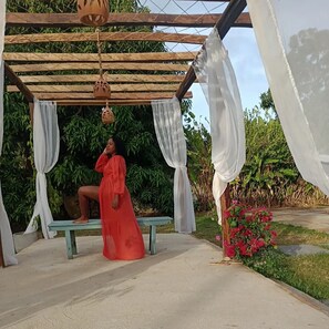 A covered outdoor seating area with a bench, white drapes, and hanging lanterns. - Delta Park (Parnaíba)