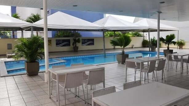 A poolside area with outdoor seating and umbrellas. - Hotel Executive Flat Arrey (Teresina)