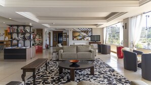 Amplia sala de estar con sofá, una mesita de centro y una estantería. Se observa una escalera al fondo que conduce a un nivel superior.
