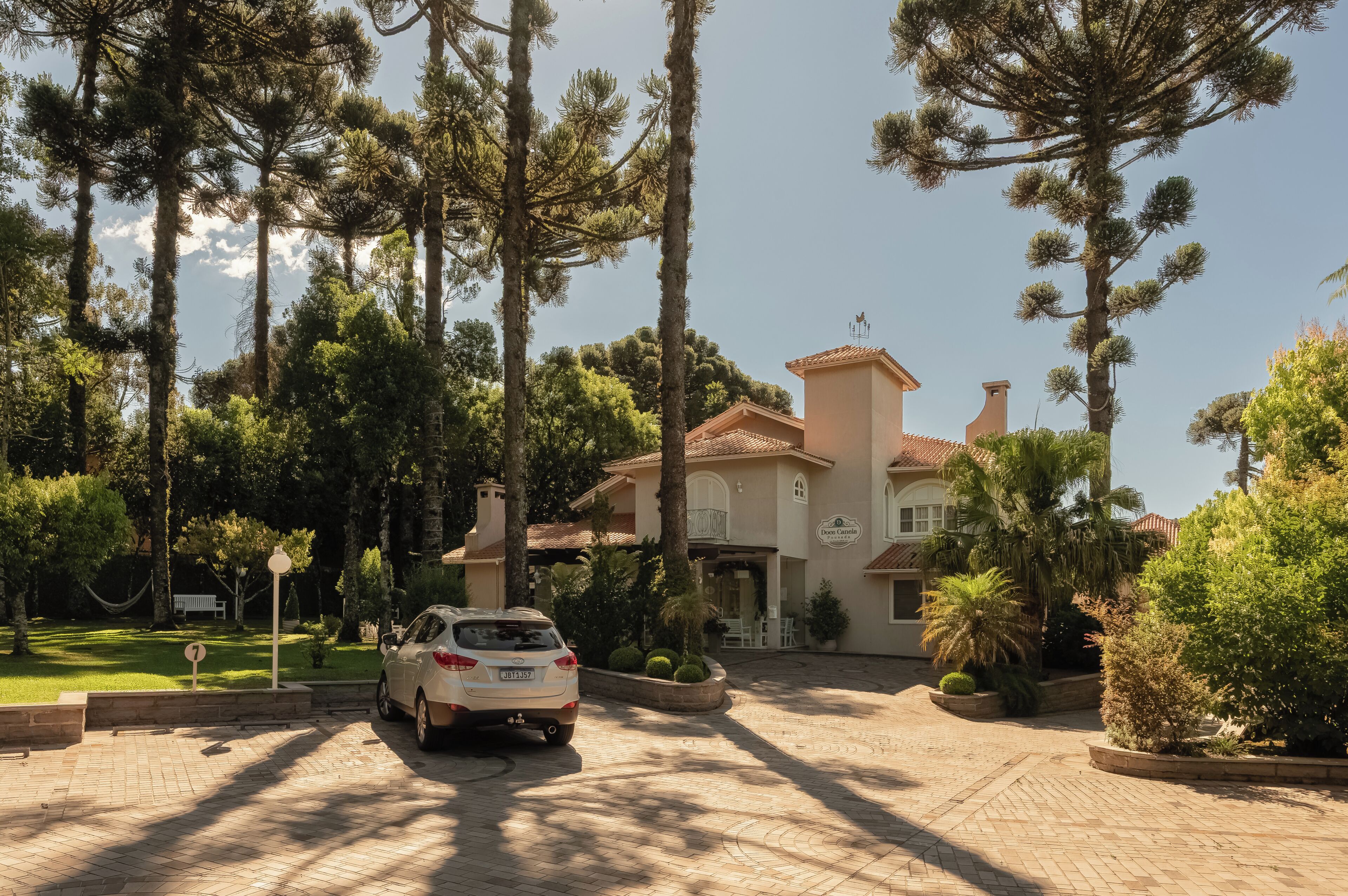 A house with a driveway, parked car, and surrounding trees.