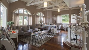 A spacious living room with high ceilings, large windows, and a cozy seating area. - Pousada Doce Canela (Canela)