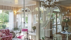 A spacious interior with a high ceiling, a balcony with ornate railings, and a chandelier. - Pousada Doce Canela (Canela)