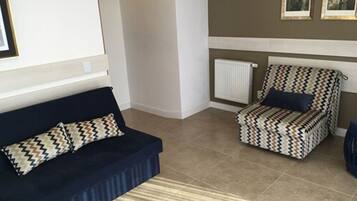 A living room with a dark blue sofa, a patterned armchair, and a striped rug.