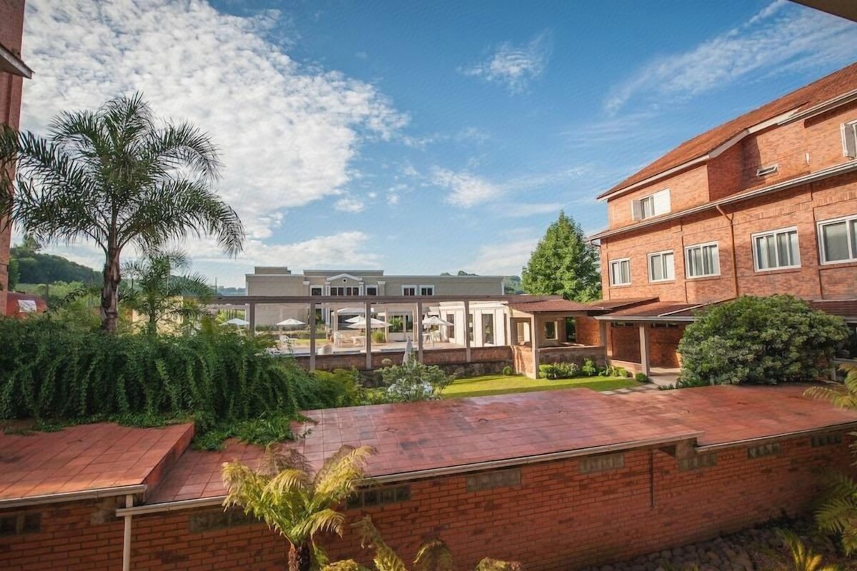 Ein Wohngebäude mit überdachter Terrasse, einer Ziegel-Fassade und blauem Himmel.