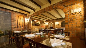Een restaurant met bakstenen muren, houten balken en gedekte tafels.