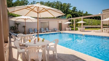 Una piscina al aire libre de temporada, sombrillas