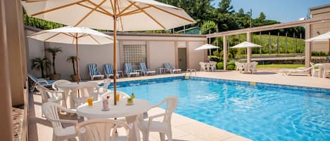 Una piscina al aire libre de temporada, sombrillas