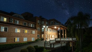 Een meerlaags hotel met een overdekt buitengebied, meerdere ramen en een sterrenhemel.