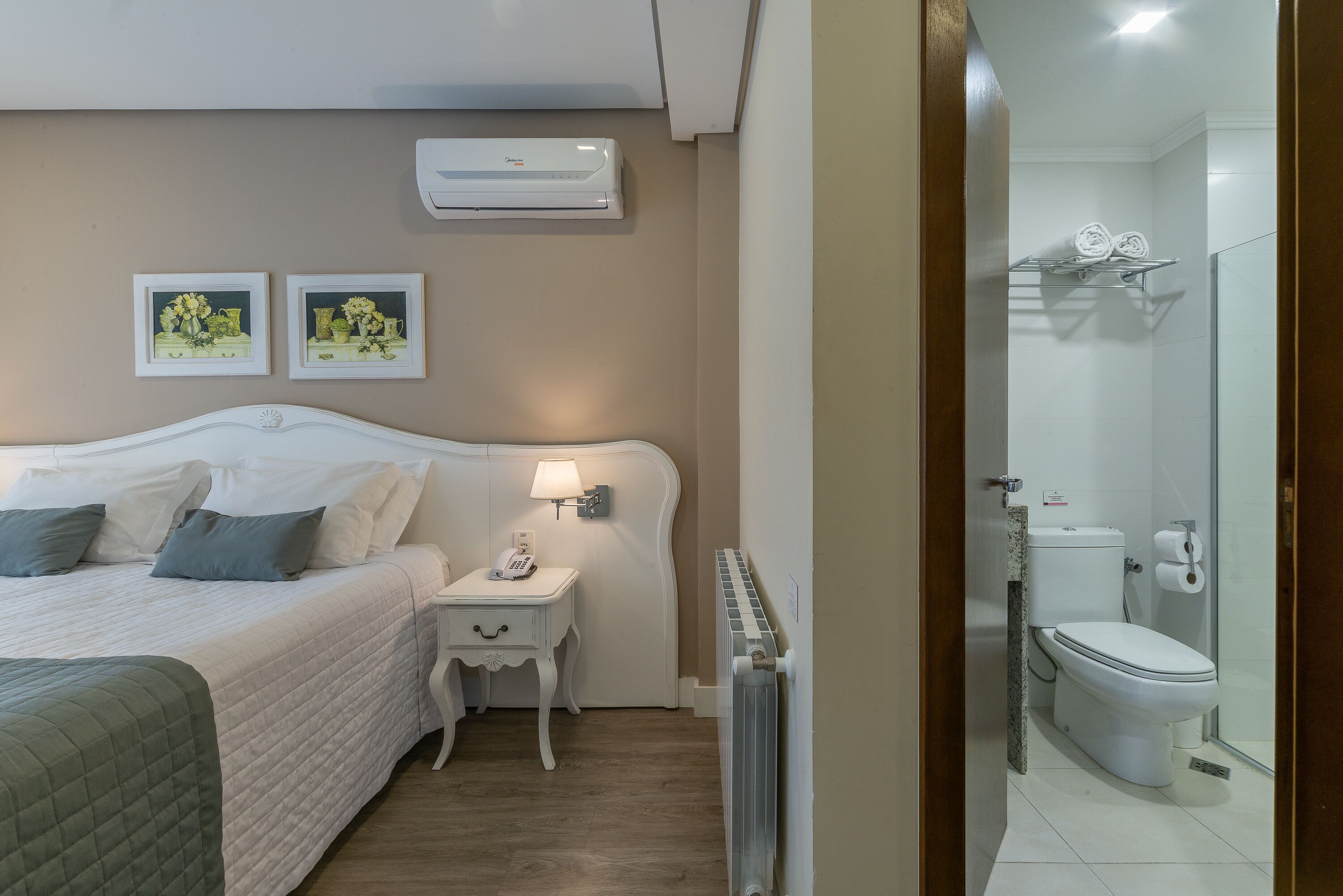 A hotel room with a bed, bedside table, lamp, and a view of the bathroom.
