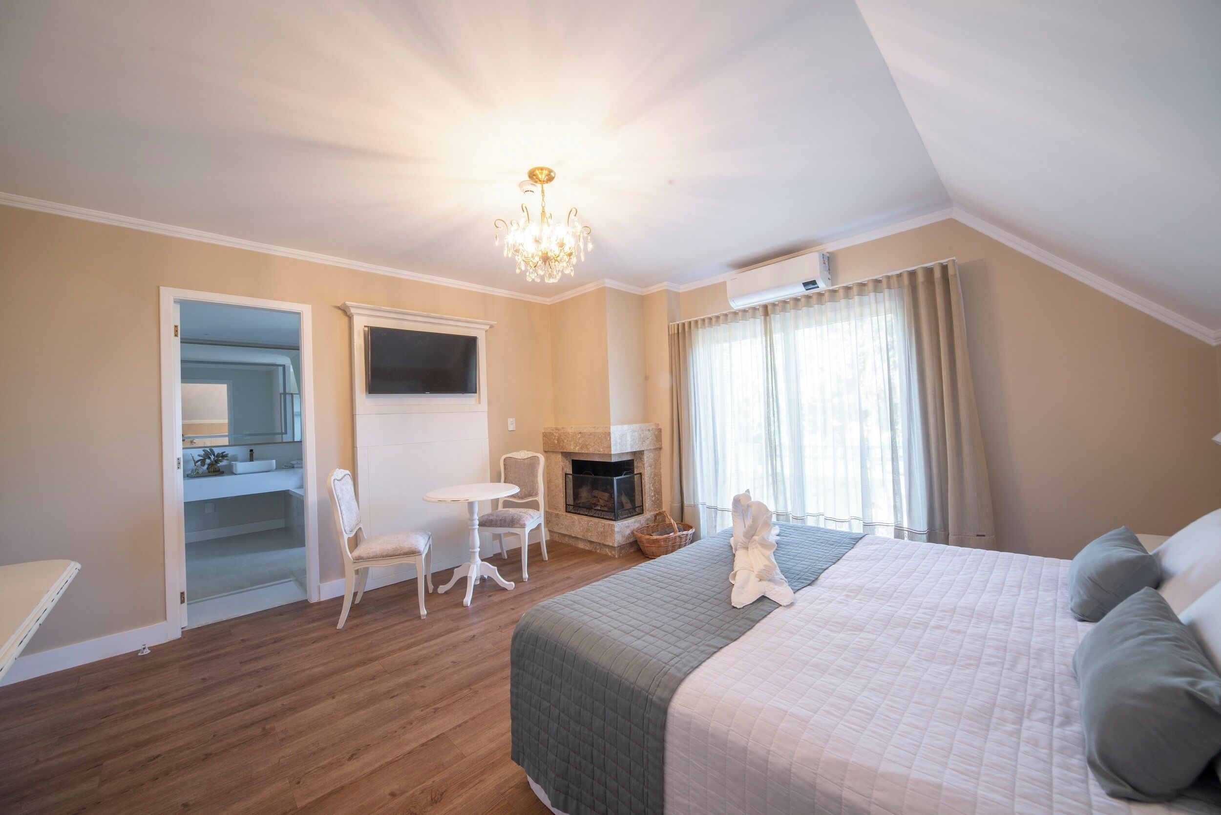 Un dormitorio con cama, chimenea, candelabro y vistas al exterior.
