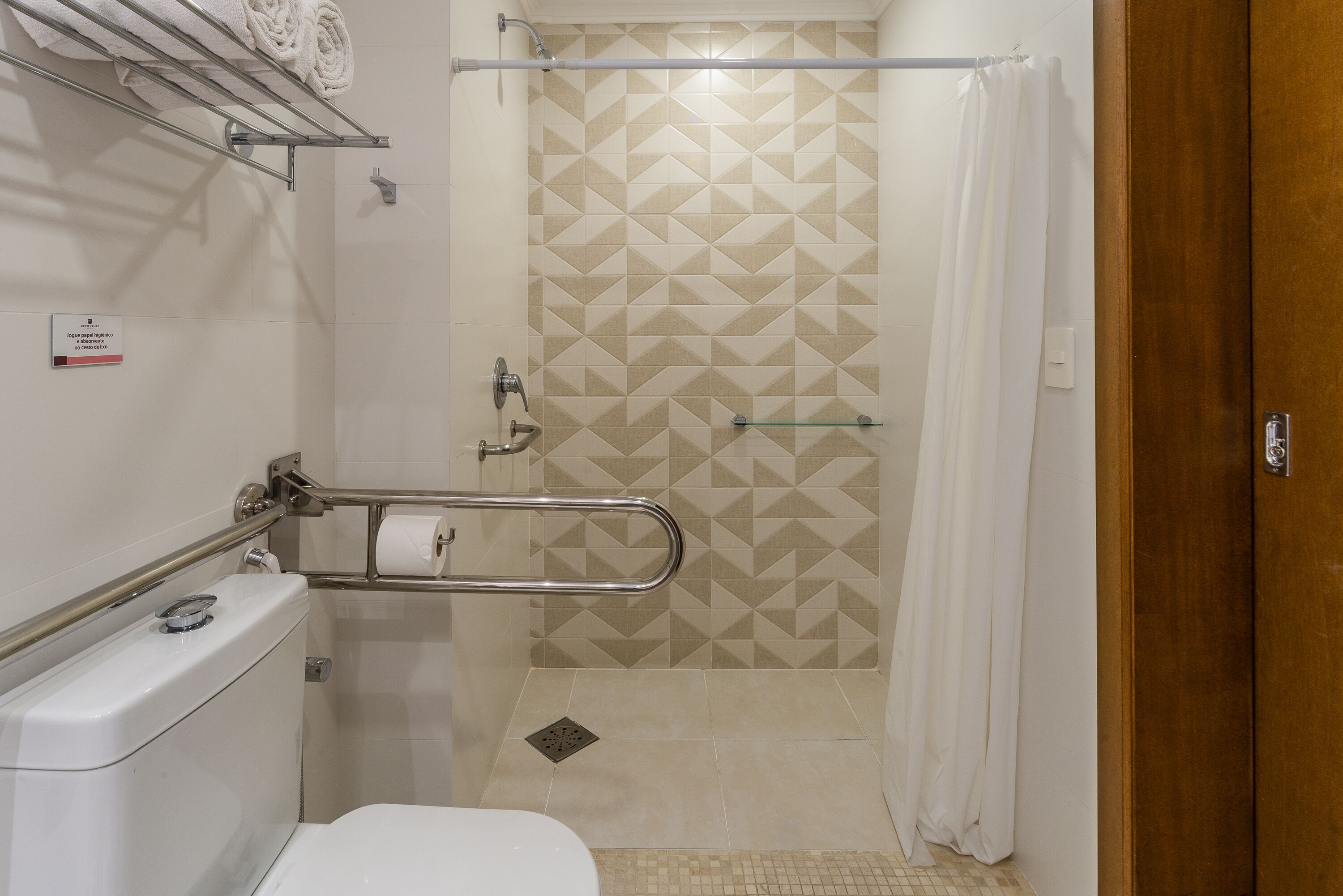 A bathroom with a toilet, a shower with a glass door, and a towel rack.