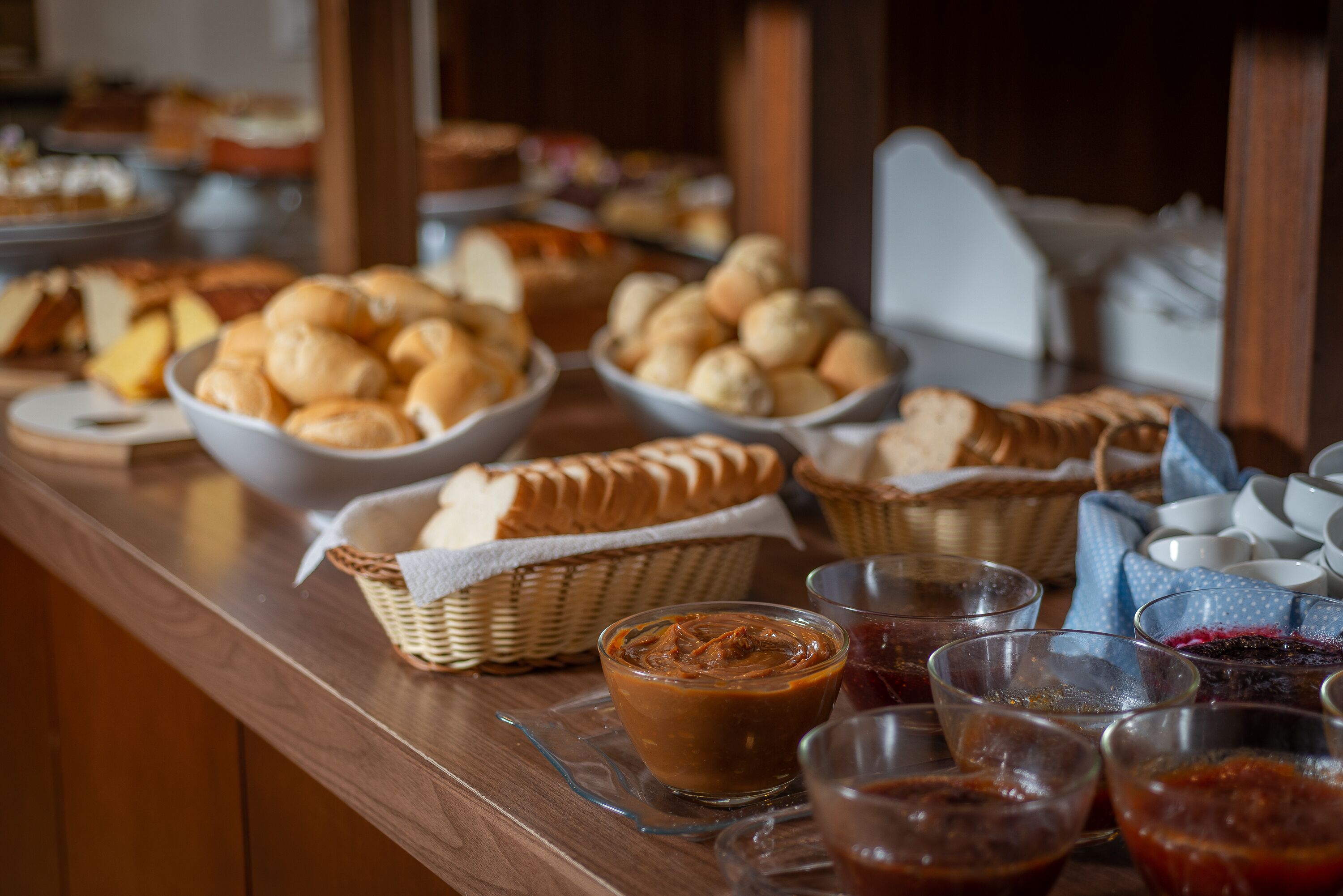 A buffet table with various breads, baskets, and small bowls of condiments.