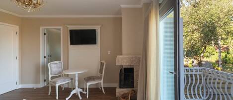 A balcony with a view of trees, a fireplace, and a television mounted on the wall.