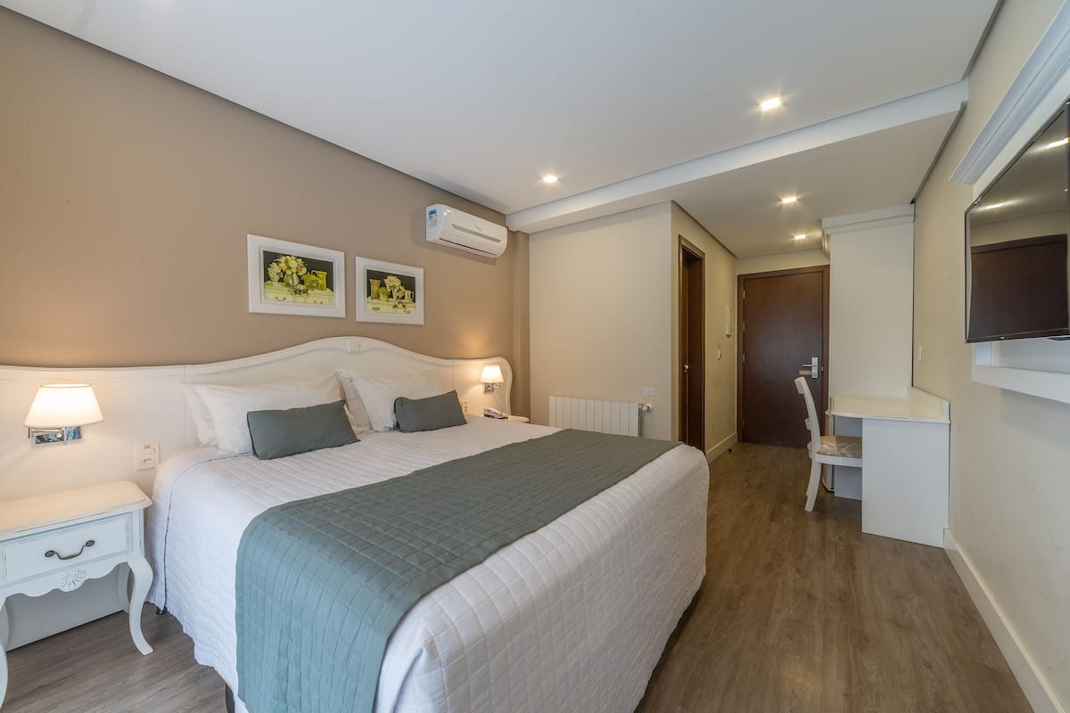 A bedroom with a bed, bedside tables, a desk, and a chair.