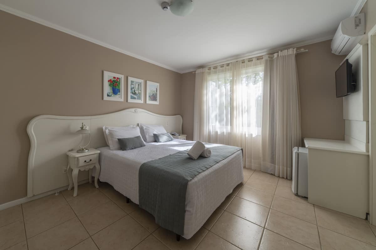 A neatly arranged bedroom with a bed, bedside table, and a TV mounted on the wall.