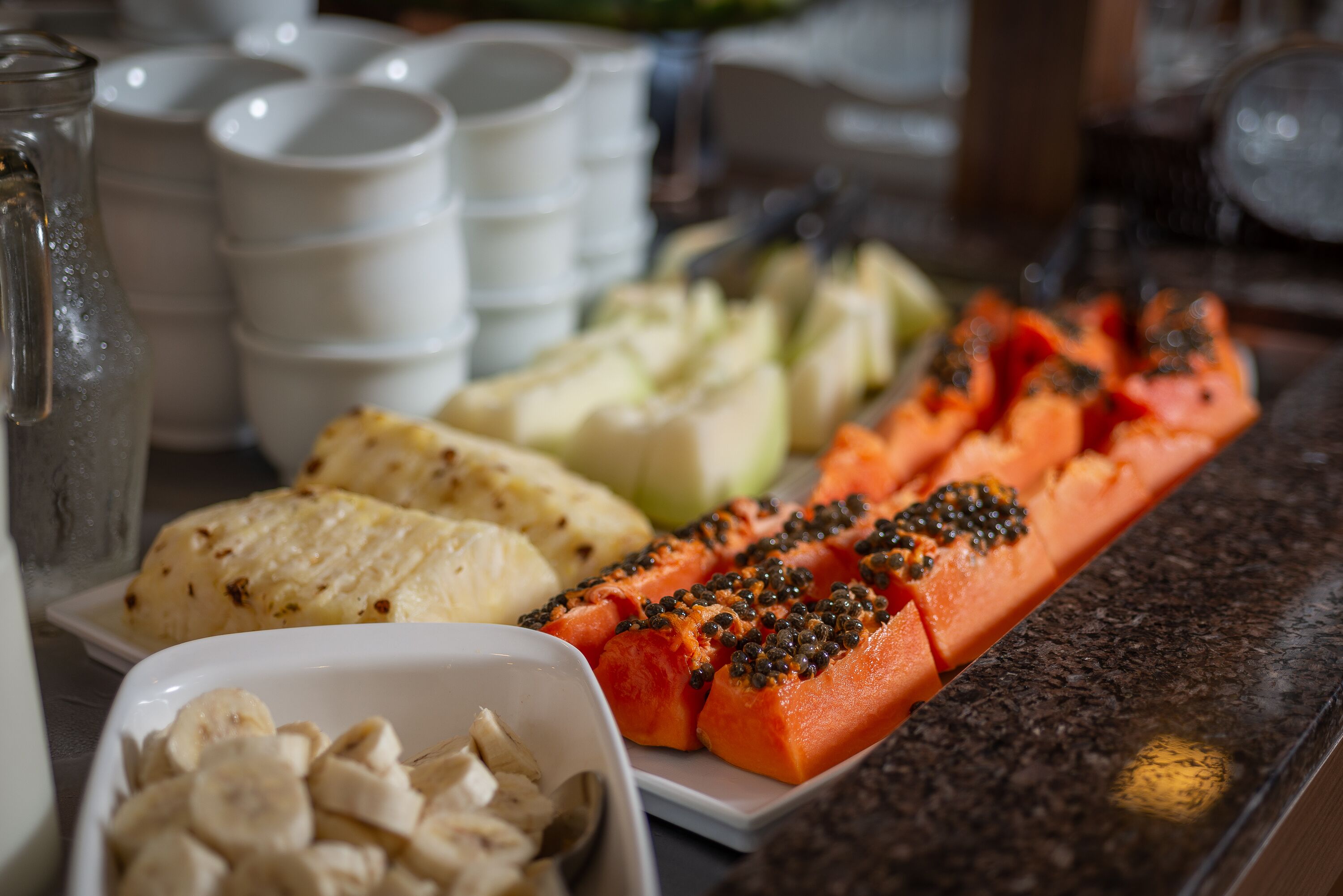 A buffet with various dishes including sliced bananas, carrots, and other vegetables.