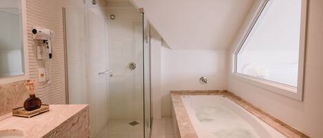Un baño moderno con ducha de vidrio, una bañera grande y un lavamanos con encimera de mármol.